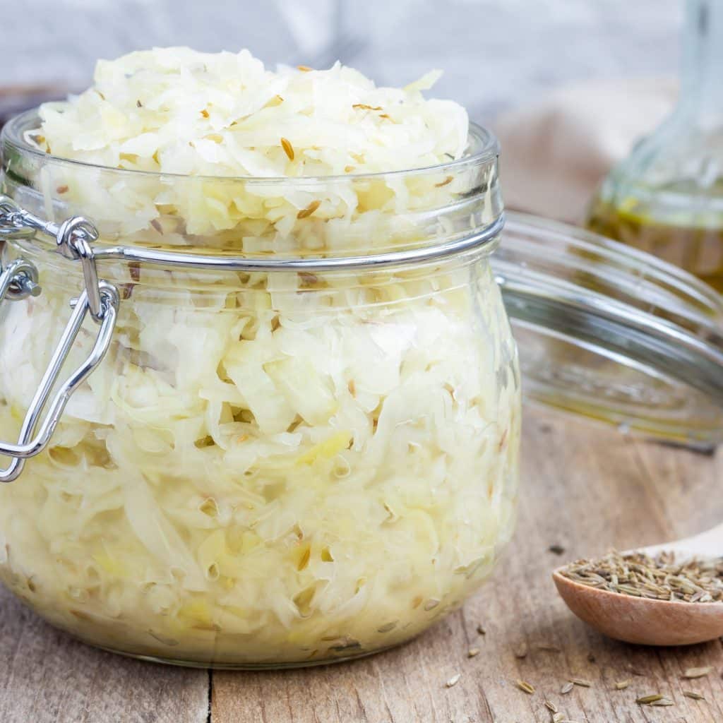 Homemade sauerkraut with cumin in a glass jar, closeup, square format
