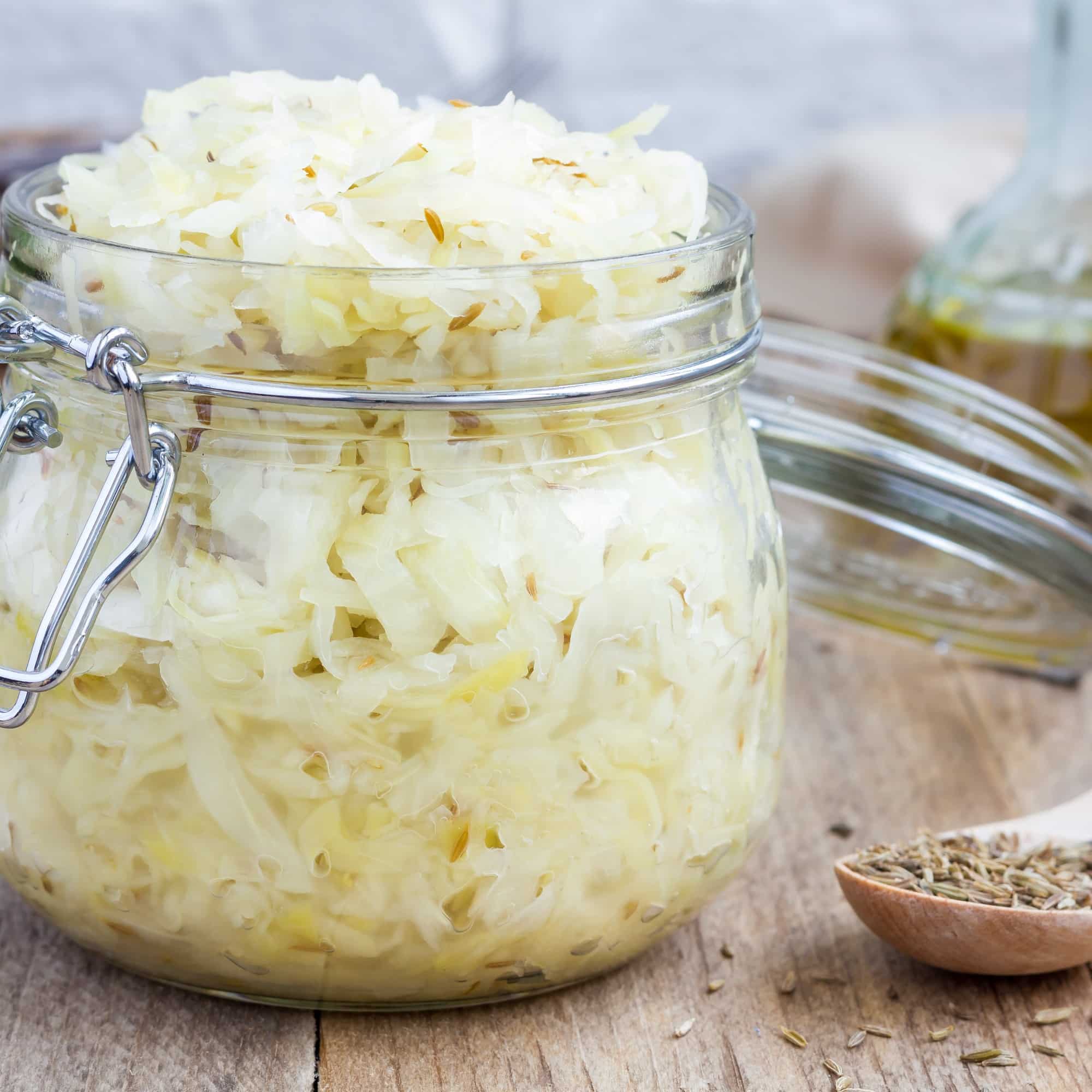Homemade sauerkraut with cumin in a glass jar, closeup, square format