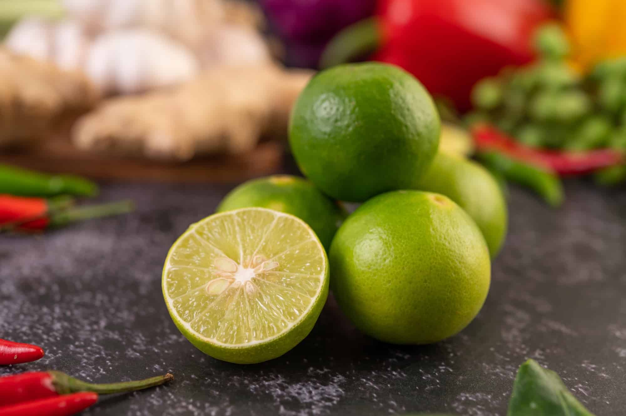 Lime piles on the floor with kaffir lime leaves. Chilli and ginger.